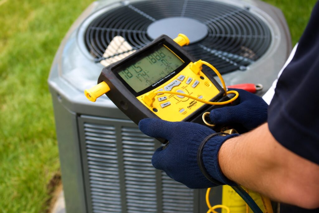 technician-holding-hvac-guagues-air-conditioner