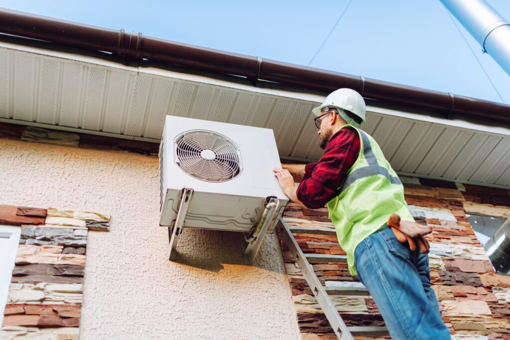 A technician works outdoors on an HVAC unit.