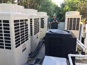  HVAC tech working on Carrier HVAC units outside of home 